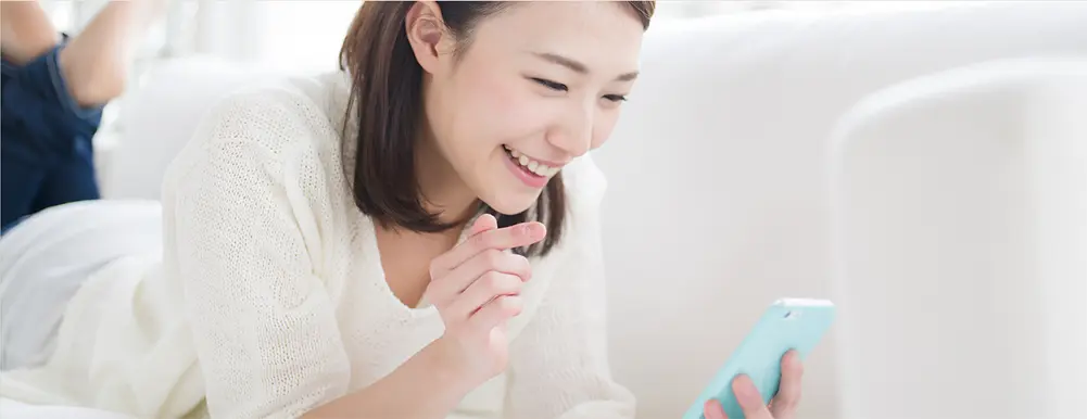 女性が寝転びながらスマホをみる